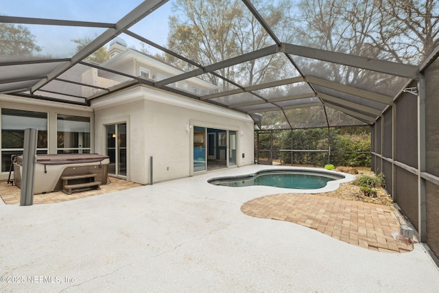 outdoor pool with a patio area, glass enclosure, and a hot tub