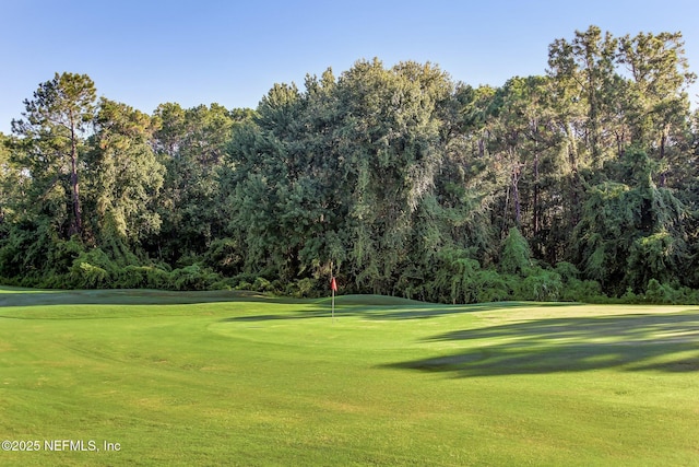 view of property's community with a lawn and view of golf course