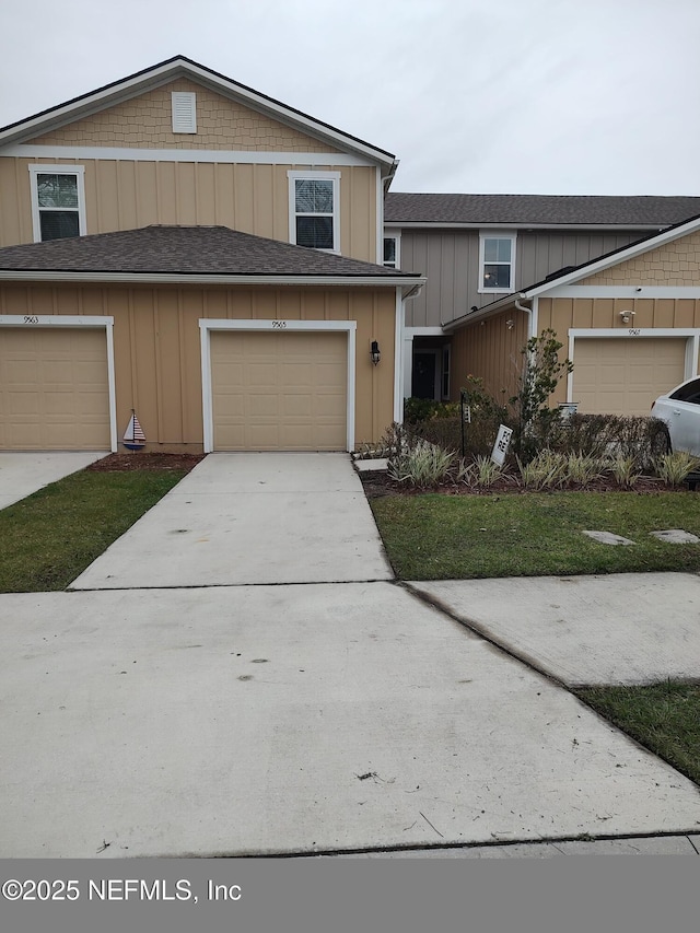 view of front of house with an attached garage, concrete driveway, roof with shingles, and board and batten siding