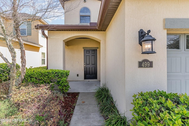 doorway to property featuring stucco siding and a garage