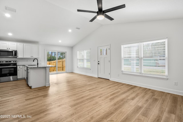 kitchen with light wood finished floors, visible vents, light stone countertops, appliances with stainless steel finishes, and a peninsula