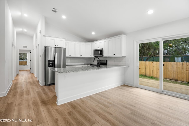 kitchen featuring light stone counters, a peninsula, a sink, white cabinets, and appliances with stainless steel finishes