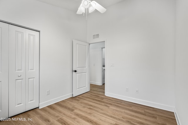 unfurnished bedroom with a closet, visible vents, baseboards, and wood finished floors