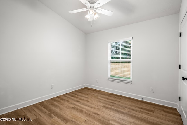 spare room featuring baseboards, wood finished floors, and a ceiling fan