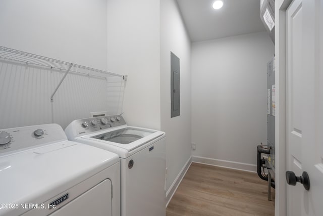 washroom featuring light wood-type flooring, electric panel, baseboards, laundry area, and washing machine and clothes dryer