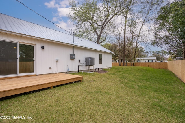 view of yard featuring a deck, fence, and central AC