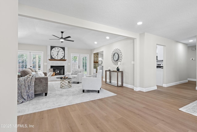 unfurnished living room with french doors, a fireplace, a textured ceiling, and wood finished floors