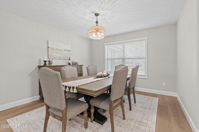 dining room featuring wood finished floors, baseboards, and a chandelier