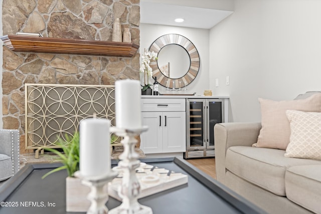 living room with wine cooler, a fireplace, a bar, and wood finished floors