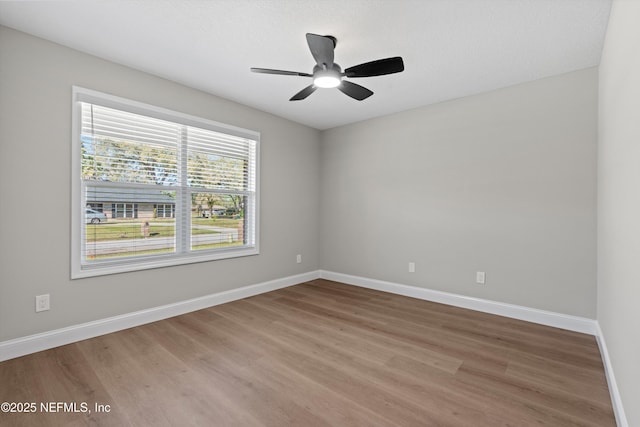 spare room with a ceiling fan, wood finished floors, and baseboards