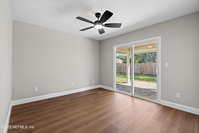 empty room featuring wood finished floors, baseboards, and a textured ceiling