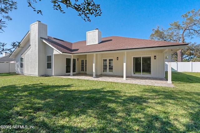 rear view of house featuring a patio, fence, french doors, a yard, and a chimney