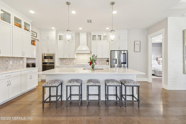 83 Village Grande Dr, Ponte Vedra, FL 32081 - kitchen with visible vents, custom exhaust hood, a kitchen island with sink, stainless steel appliances, and a kitchen bar