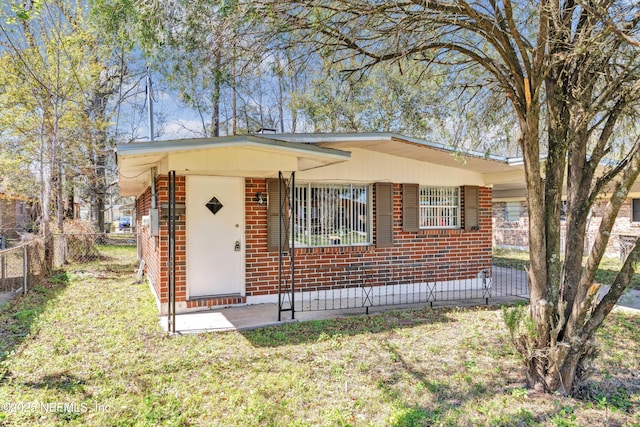 view of front facade featuring a front yard, fence, and brick siding