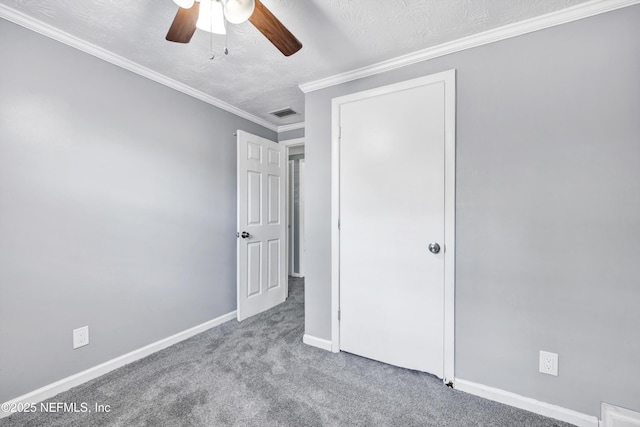 unfurnished bedroom featuring visible vents, a textured ceiling, carpet floors, crown molding, and baseboards