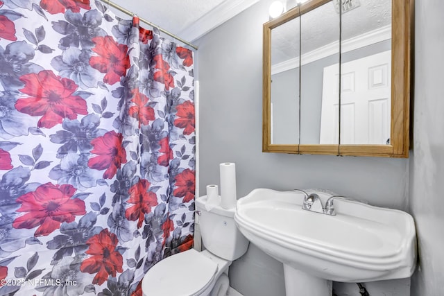 bathroom featuring crown molding, toilet, a shower with shower curtain, a textured ceiling, and a sink