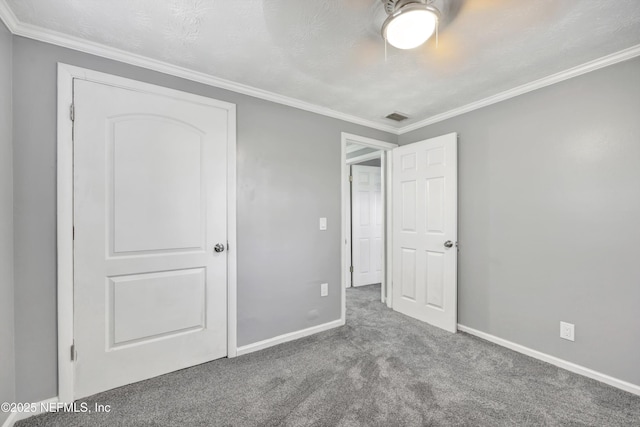 unfurnished bedroom with visible vents, a textured ceiling, carpet, crown molding, and baseboards