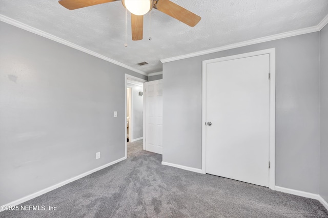 unfurnished bedroom with carpet flooring, a textured ceiling, crown molding, and baseboards