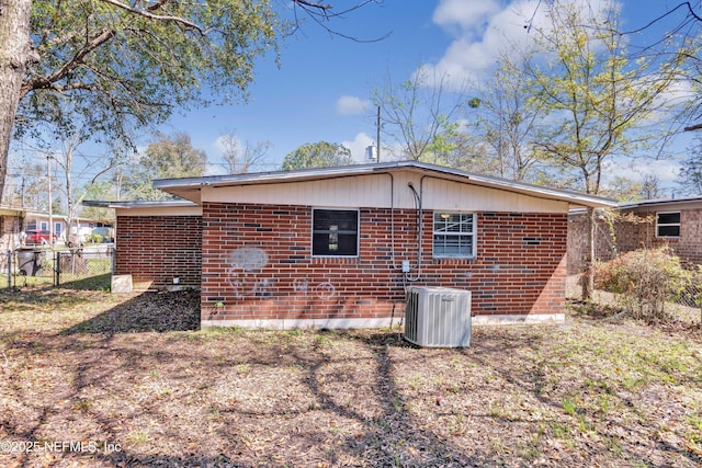 back of house featuring central air condition unit, fence, and brick siding