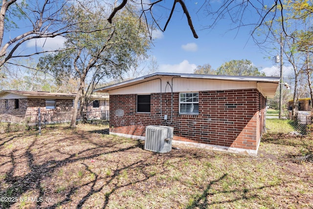 back of property featuring brick siding, central air condition unit, and fence