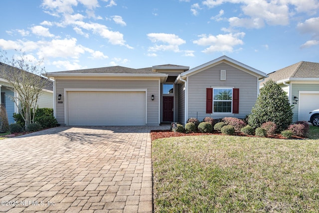 ranch-style home with decorative driveway, a garage, and a front yard