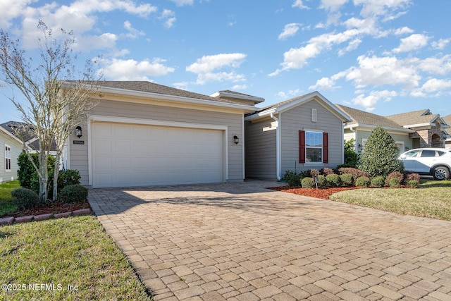 ranch-style home featuring decorative driveway and an attached garage