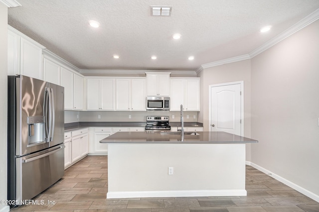 kitchen featuring an island with sink, a sink, stainless steel appliances, white cabinets, and wood tiled floor