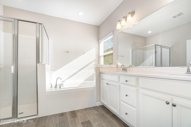 bathroom with visible vents, a garden tub, a stall shower, a sink, and wood tiled floor