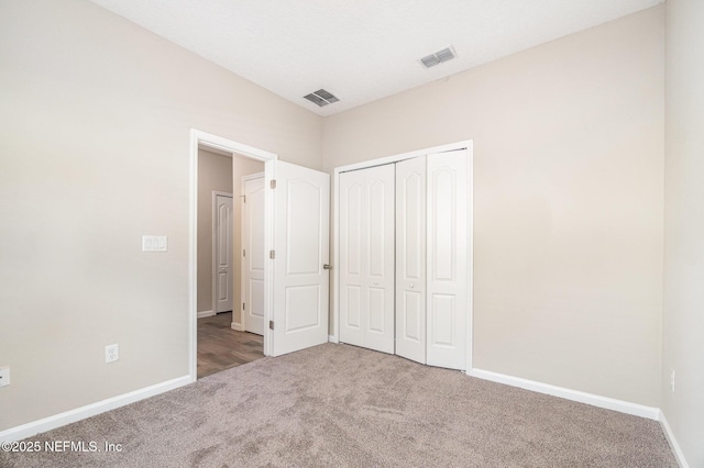 unfurnished bedroom featuring a closet, visible vents, baseboards, and carpet floors