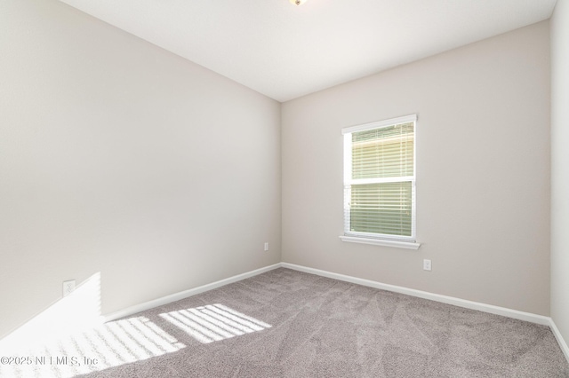 spare room with baseboards and carpet floors