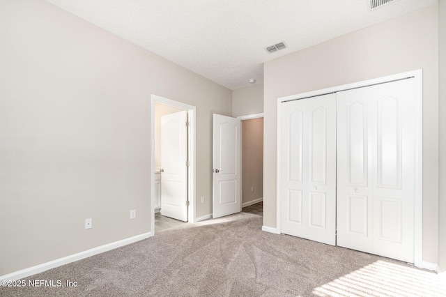 unfurnished bedroom featuring carpet, visible vents, baseboards, a closet, and ensuite bathroom