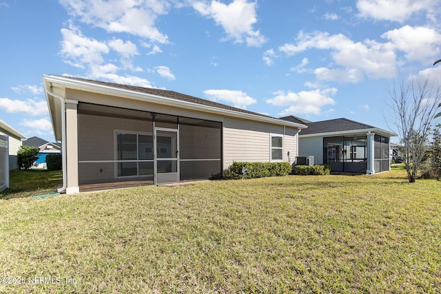 rear view of property featuring central air condition unit, a lawn, and a sunroom