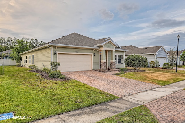 view of front facade with a garage, decorative driveway, a front lawn, and a shingled roof
