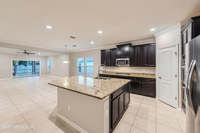 kitchen featuring appliances with stainless steel finishes, a sink, crown molding, light tile patterned flooring, and light stone countertops