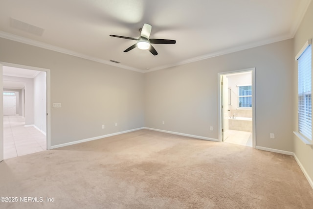 empty room featuring ceiling fan, light colored carpet, crown molding, and baseboards