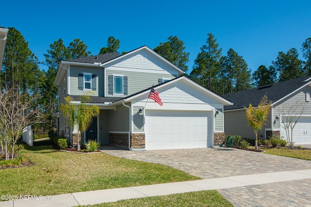 craftsman-style home with a front lawn, fence, decorative driveway, stone siding, and an attached garage