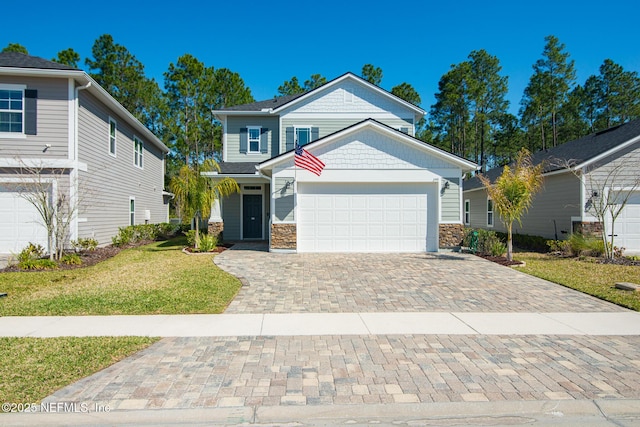 view of front of house with a front lawn, decorative driveway, a garage, and stone siding