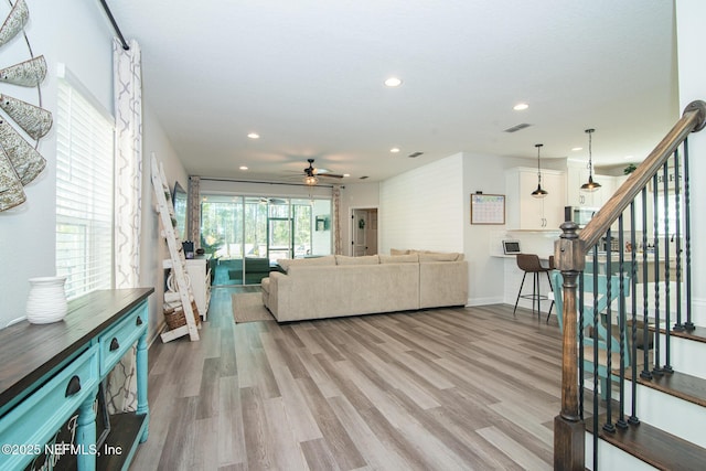 living area with stairway, visible vents, baseboards, light wood-style flooring, and recessed lighting