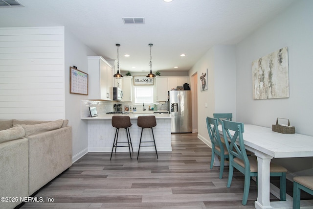 dining area featuring visible vents, baseboards, and wood finished floors