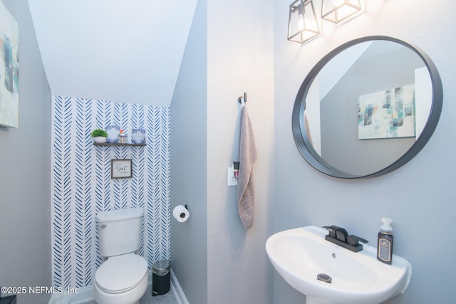 half bath featuring a sink, baseboards, and toilet