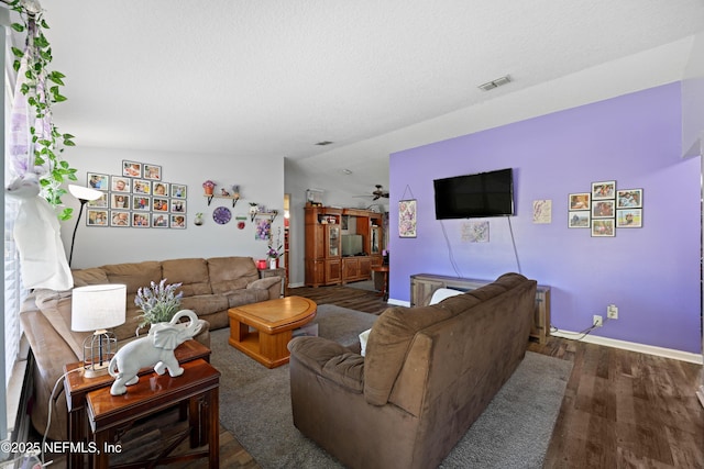 living room featuring baseboards, wood finished floors, visible vents, and ceiling fan