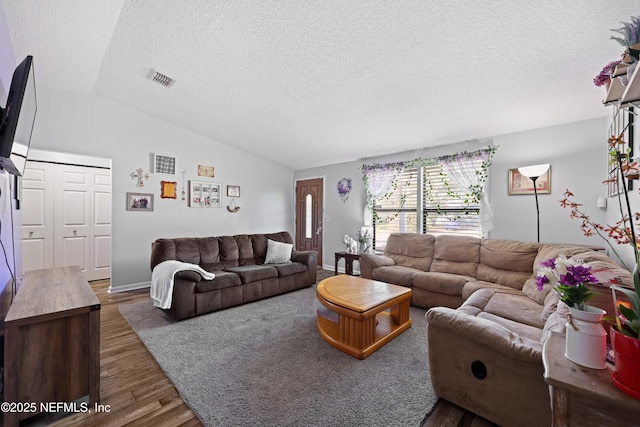 living area featuring lofted ceiling, wood finished floors, visible vents, and a textured ceiling