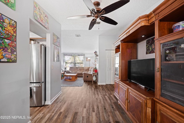 living area with baseboards, a textured ceiling, dark wood finished floors, and a ceiling fan