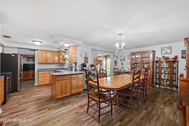 dining area with visible vents, wood finished floors, a textured ceiling, and a chandelier