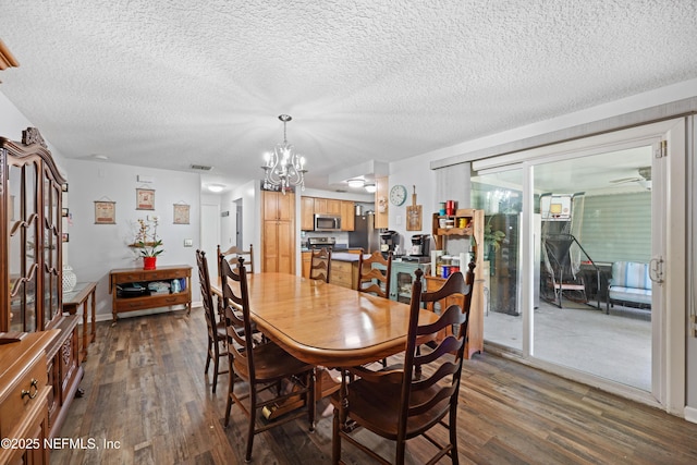 dining space featuring visible vents, a textured ceiling, an inviting chandelier, and dark wood-style flooring