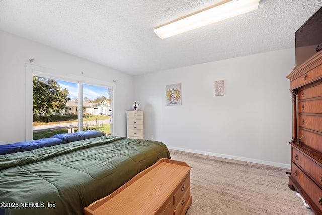 bedroom with light colored carpet, a textured ceiling, and baseboards