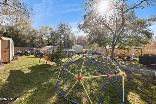 view of yard featuring a storage shed, a playground, an outbuilding, and a fenced backyard