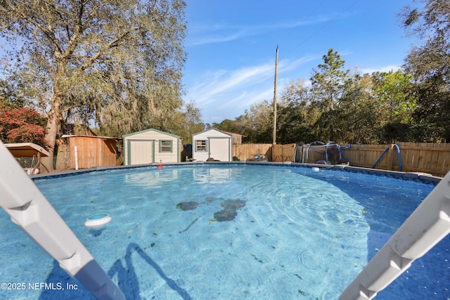 view of swimming pool with a fenced in pool, an outbuilding, a fenced backyard, and a shed