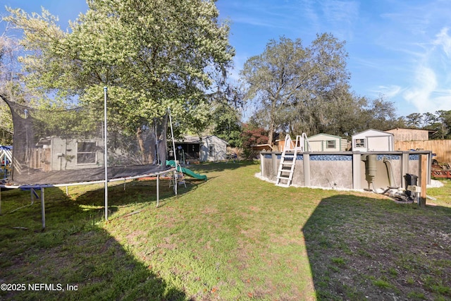 view of yard with an outdoor pool, an outbuilding, a trampoline, and a storage shed