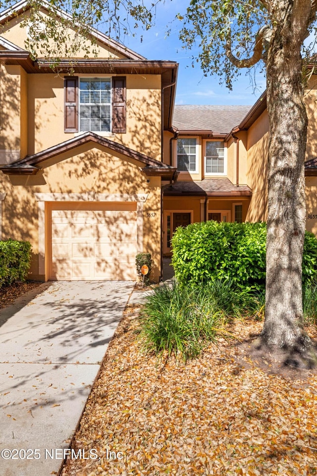 traditional-style house with a garage, driveway, and stucco siding